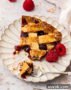 A slice of linzer tart with some cut away with a dessert fork.