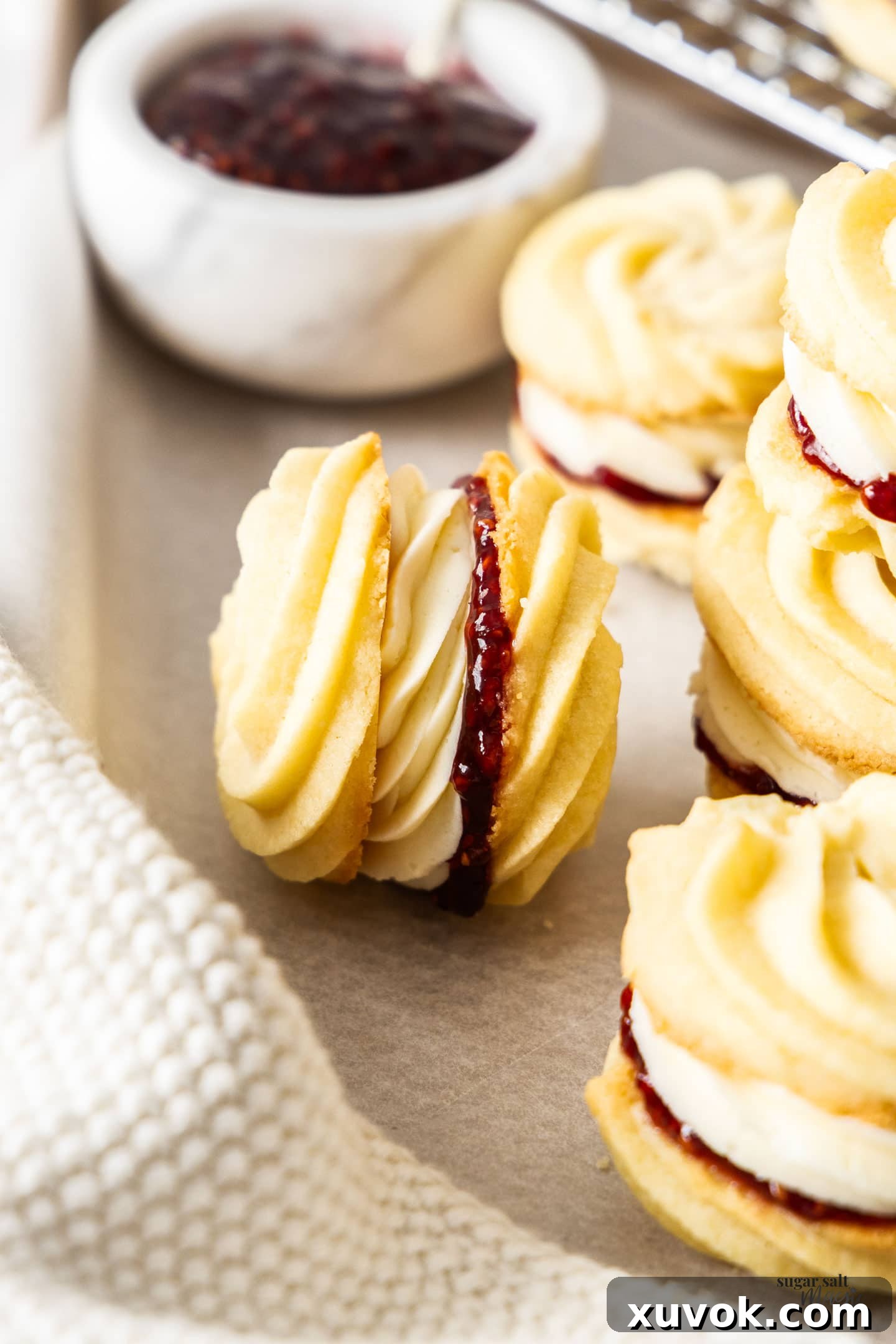 Closeup of a Viennese whirl lying on it's side, showcasing its delicate swirl and delicious filling.