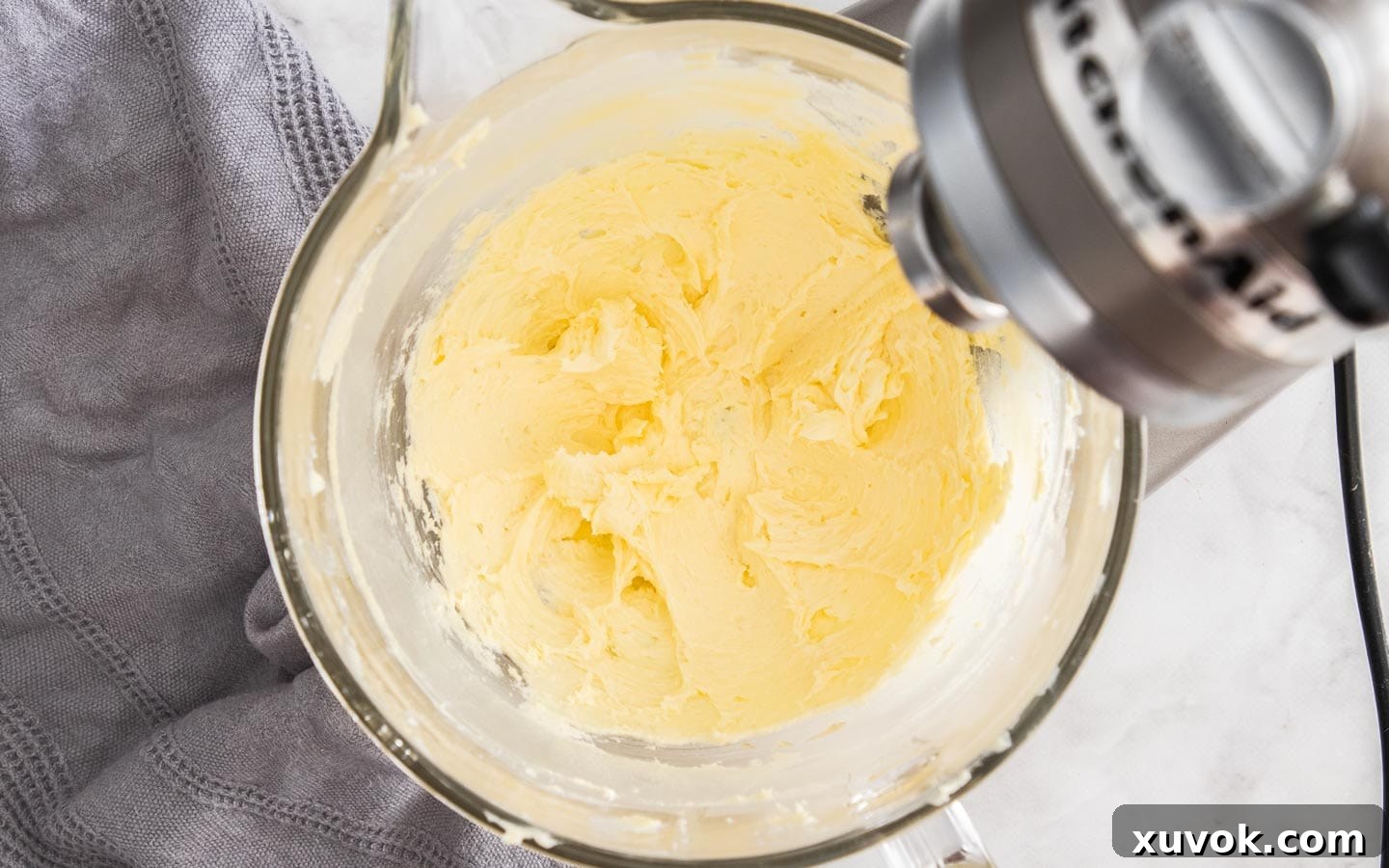 Butter and sugar beaten together in a mixing bowl, creating a light and creamy mixture.