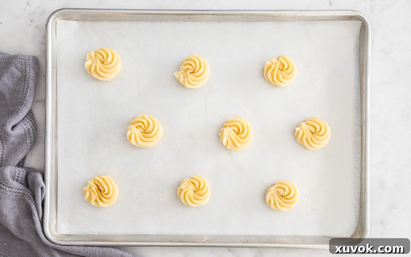 Viennese whirl cookie dough piped into rosettes on a baking sheet, ready for chilling.
