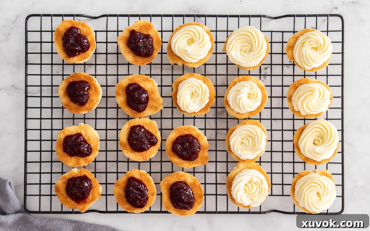 The baked Viennese whirl cookies topped with swirls of buttercream and a dollop of raspberry jam, ready to be sandwiched.