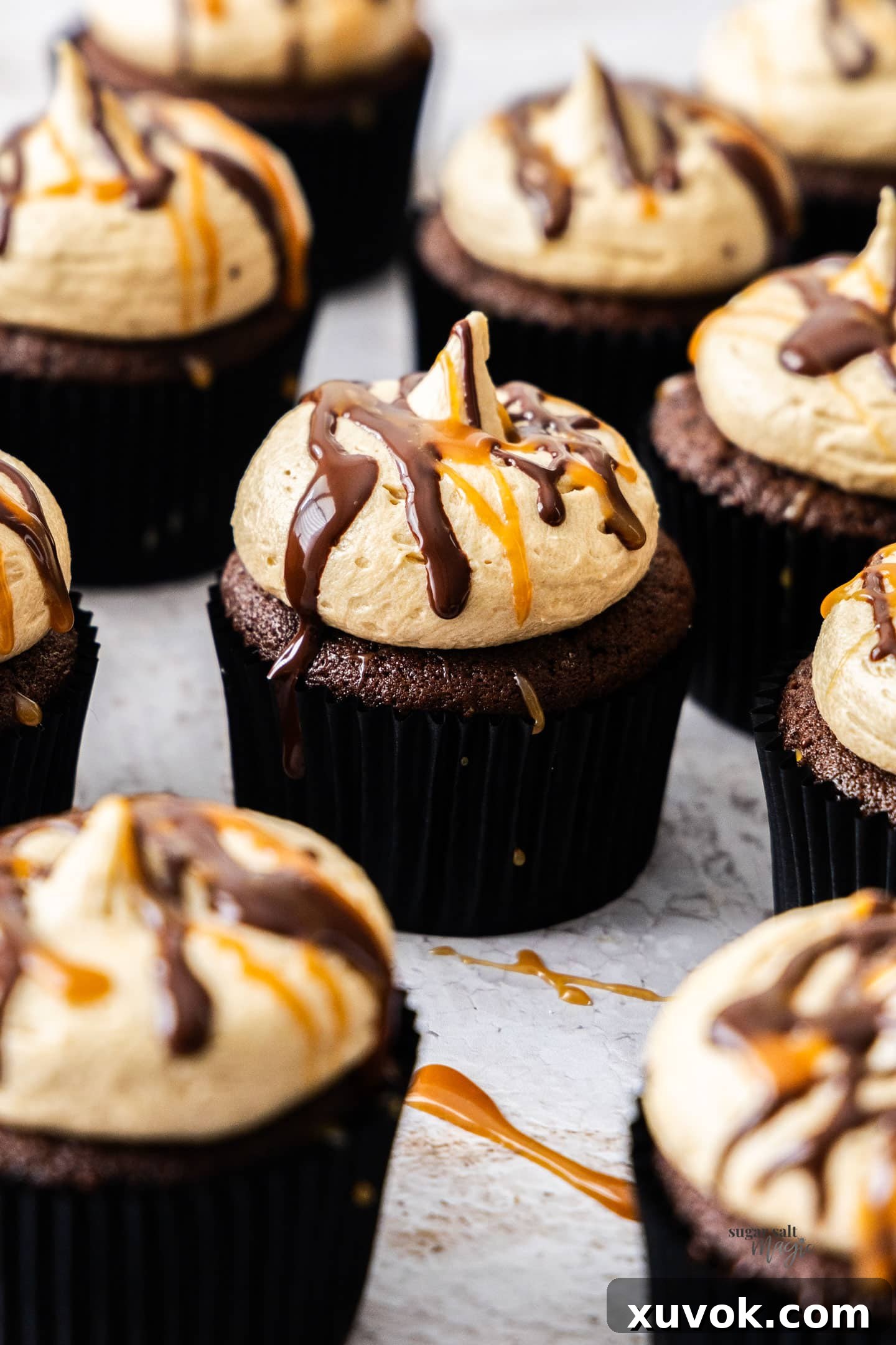 Closeup of a delectable chocolate caramel cupcake, elegantly drizzled with chocolate and caramel, nestled among a batch of equally tempting treats.