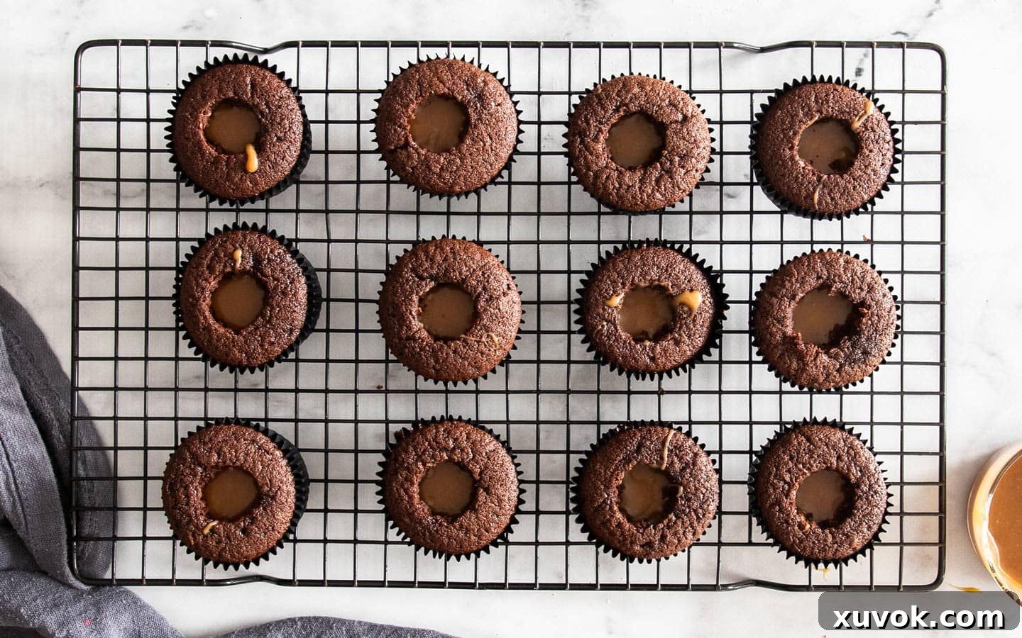 Top-down view of chocolate cupcakes with their centers cored out and generously filled with gooey caramel sauce.