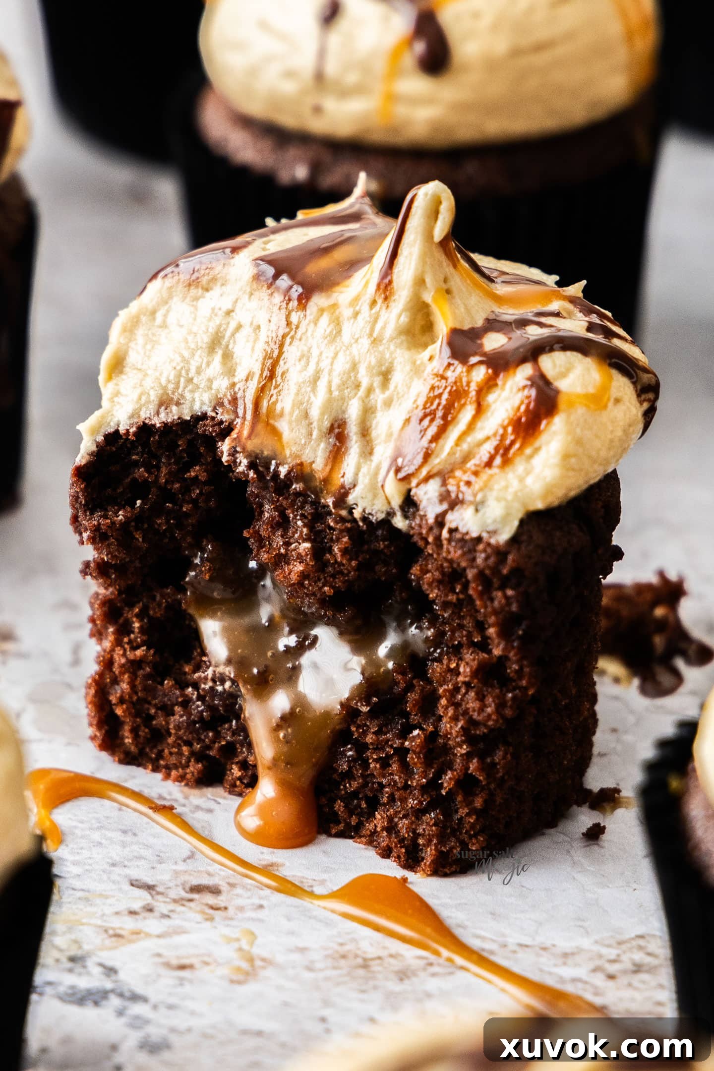 Extreme closeup of a single, perfectly cut-open chocolate caramel cupcake, revealing the luscious, oozing caramel filling within its moist chocolate interior.