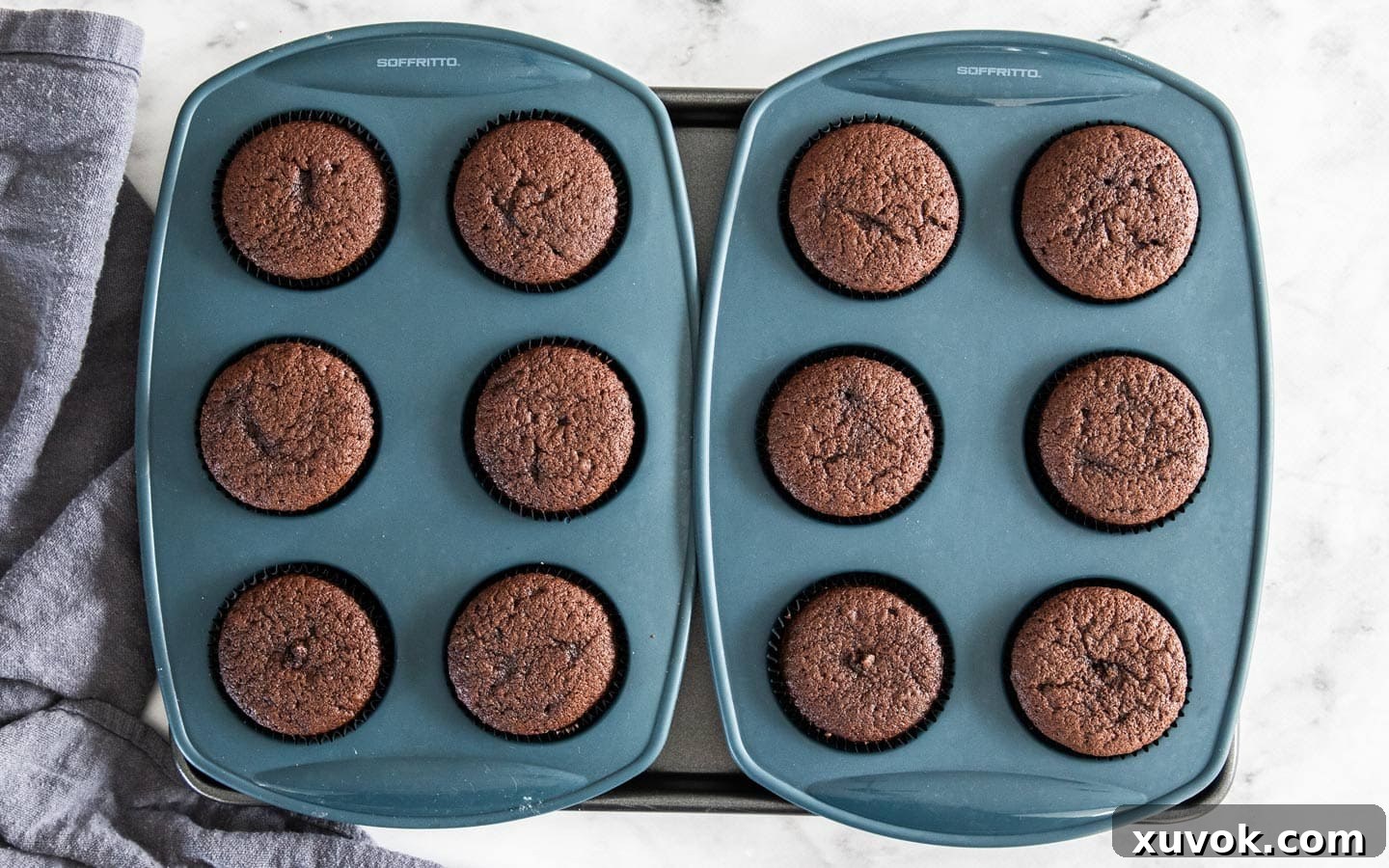 A batch of perfectly baked chocolate cupcakes cooling in silicone muffin pans, showcasing their ideal rise and shape.