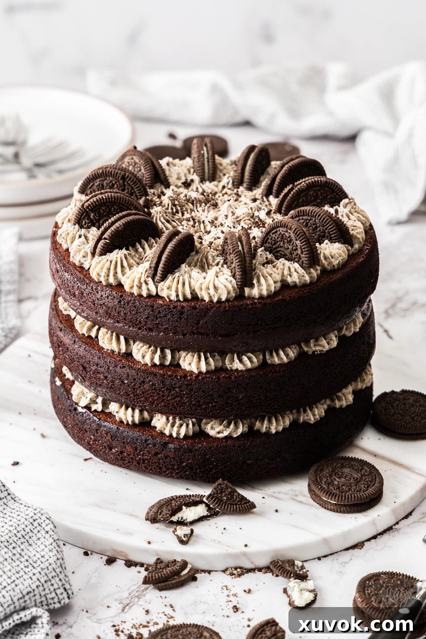 A 3 layered chocolate cake filled with Oreo buttercream on a marble platter.