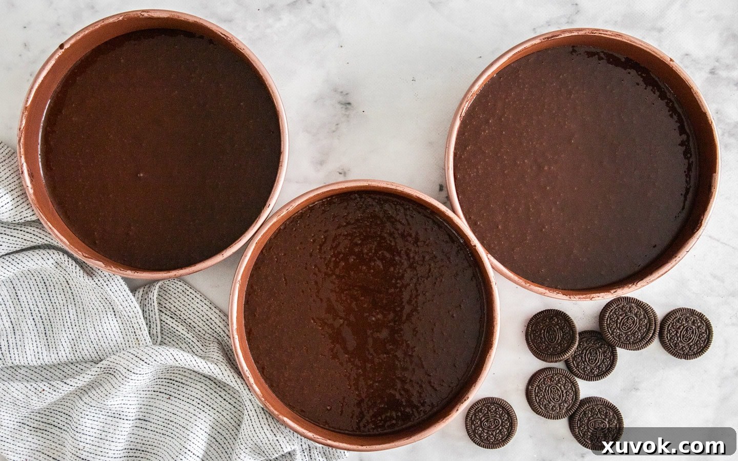 3 cake pans filled with chocolate cake batter.