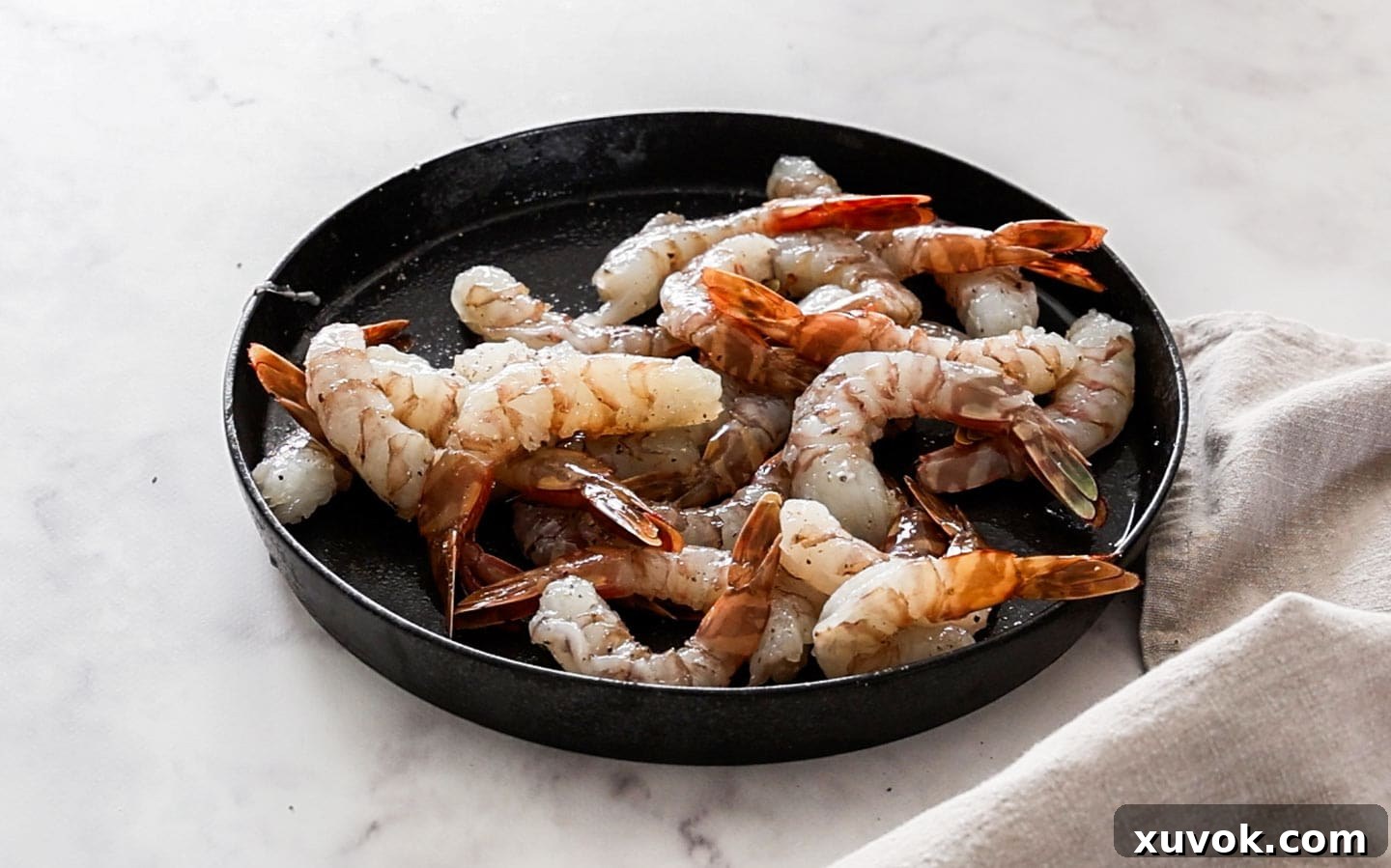 Raw prawns in a dish coated with salt and pepper, ready for breading.