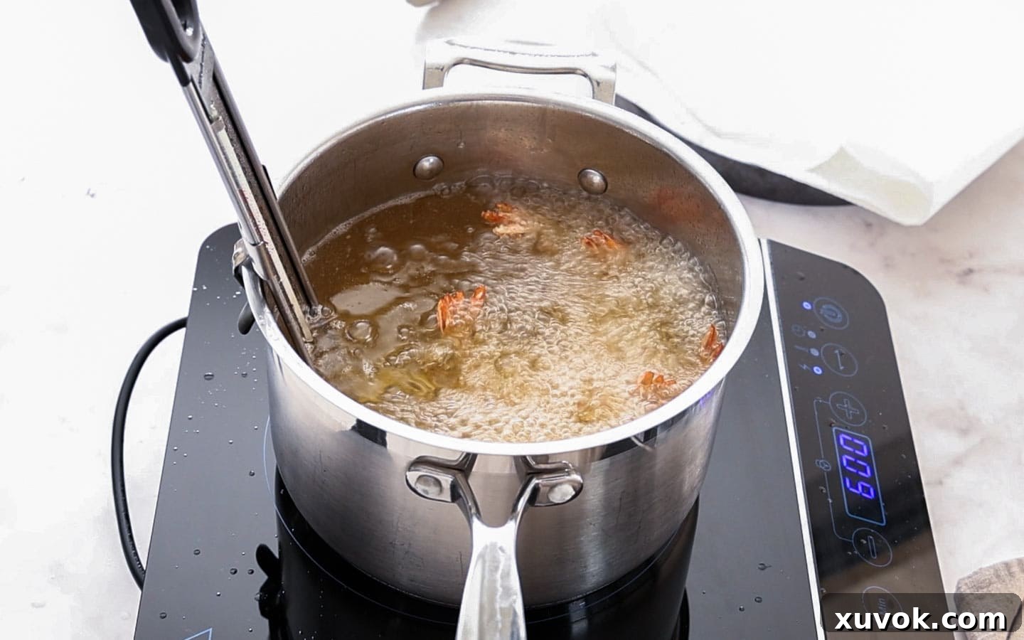 Prawn katsu frying in a saucepan on a portable cooktop, achieving a perfect golden crisp.