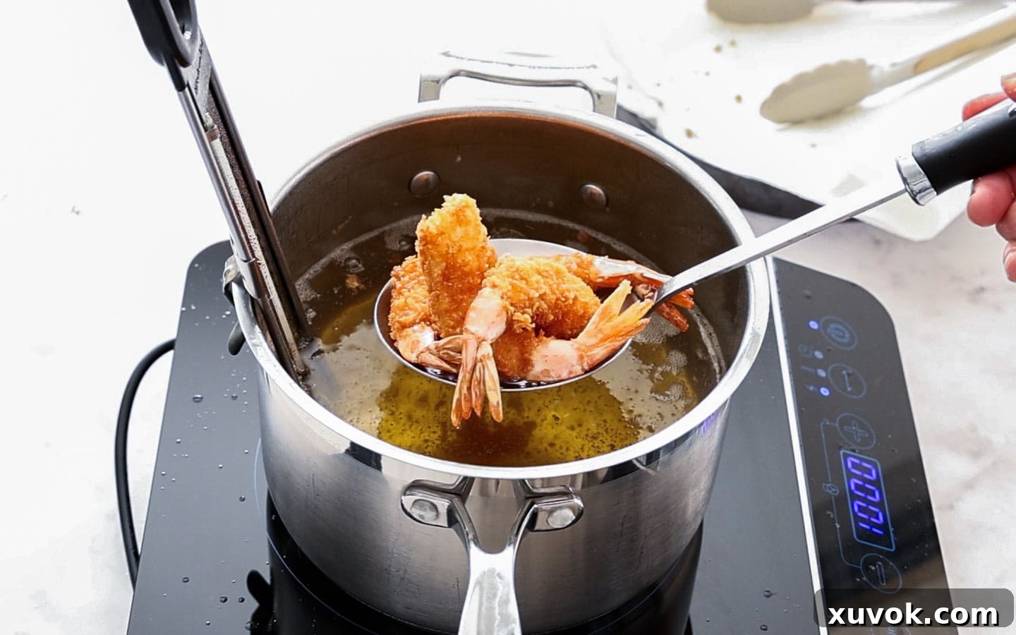 Prawn katsu being carefully taken out of the hot oil with a wire spider, golden and crispy.