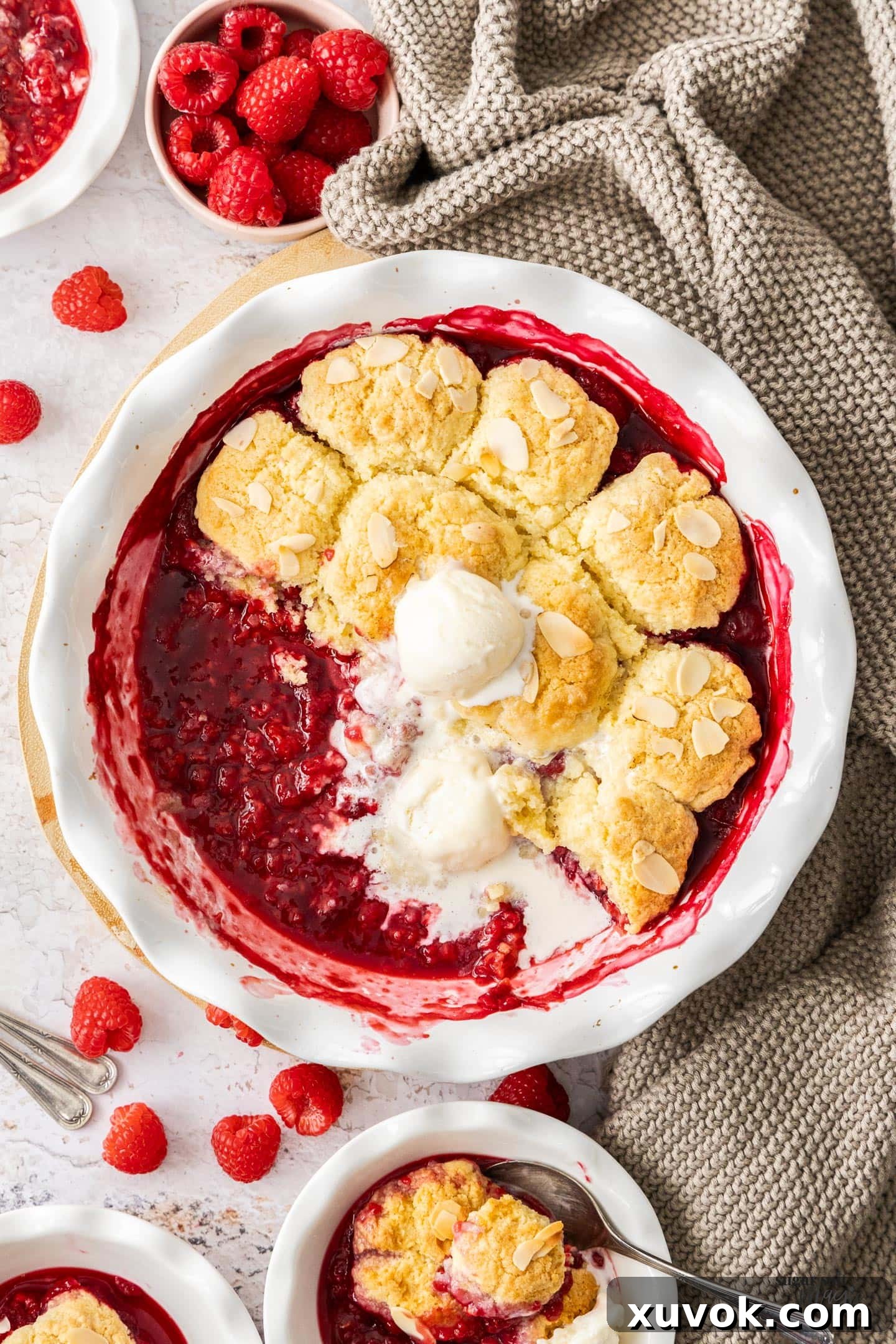 Top down view of the baked raspberry cobbler with some dessert bowls around.