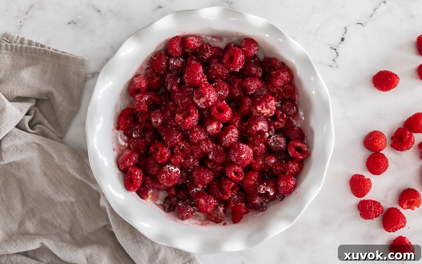 The raspberries mixed with the filling ingredients in a pie dish.