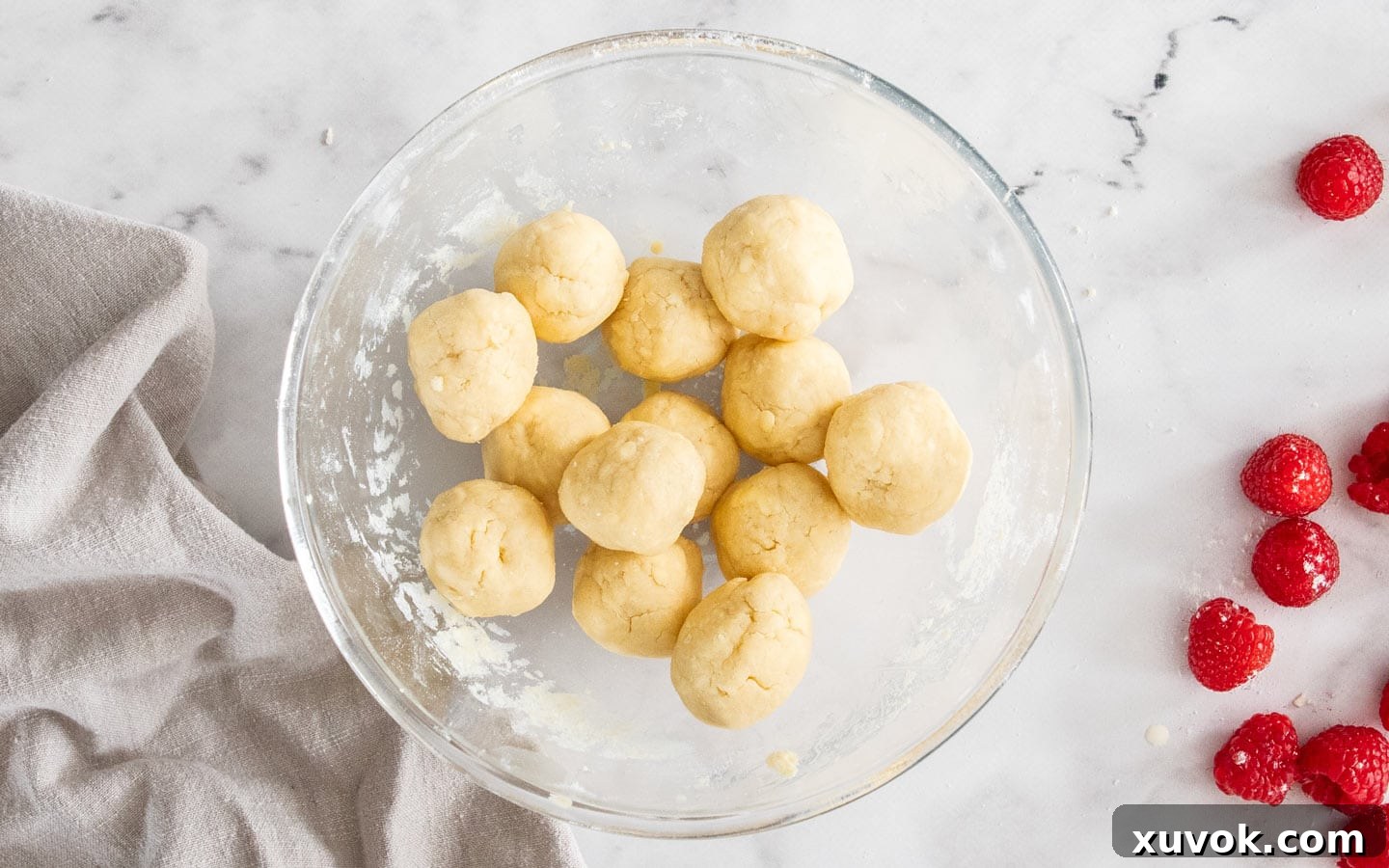 Balls of scone dough in a bowl, for topping the raspberry cobbler.
