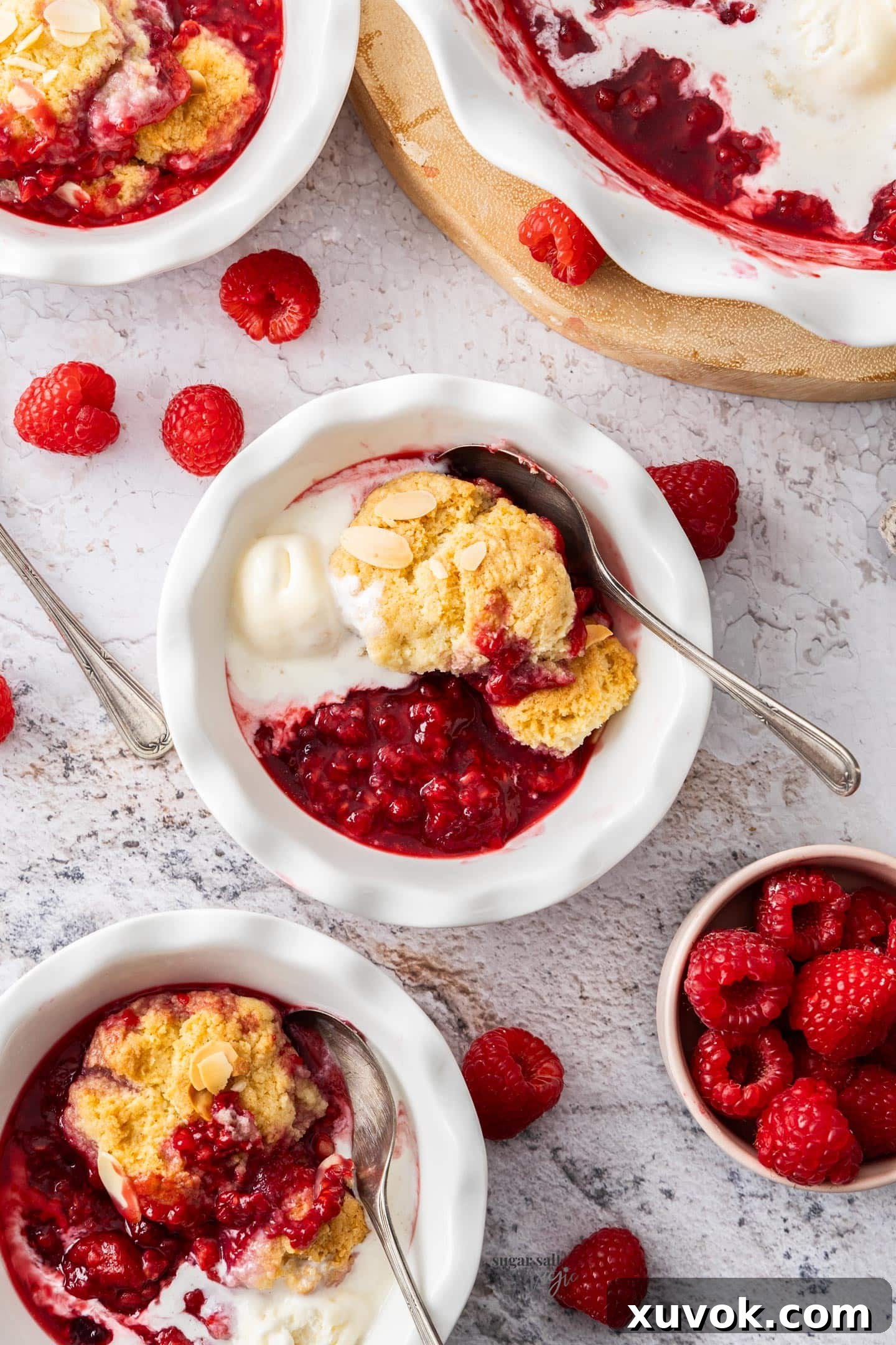 Top down view of 3 dessert bowls filled with raspberry cobbler and ice cream.