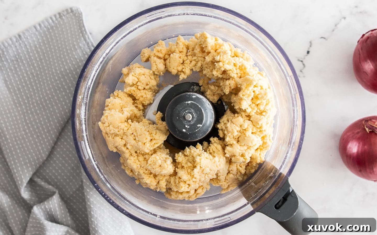 The pastry dough forming into a ball inside a food processor, indicating it's ready to be removed and chilled.