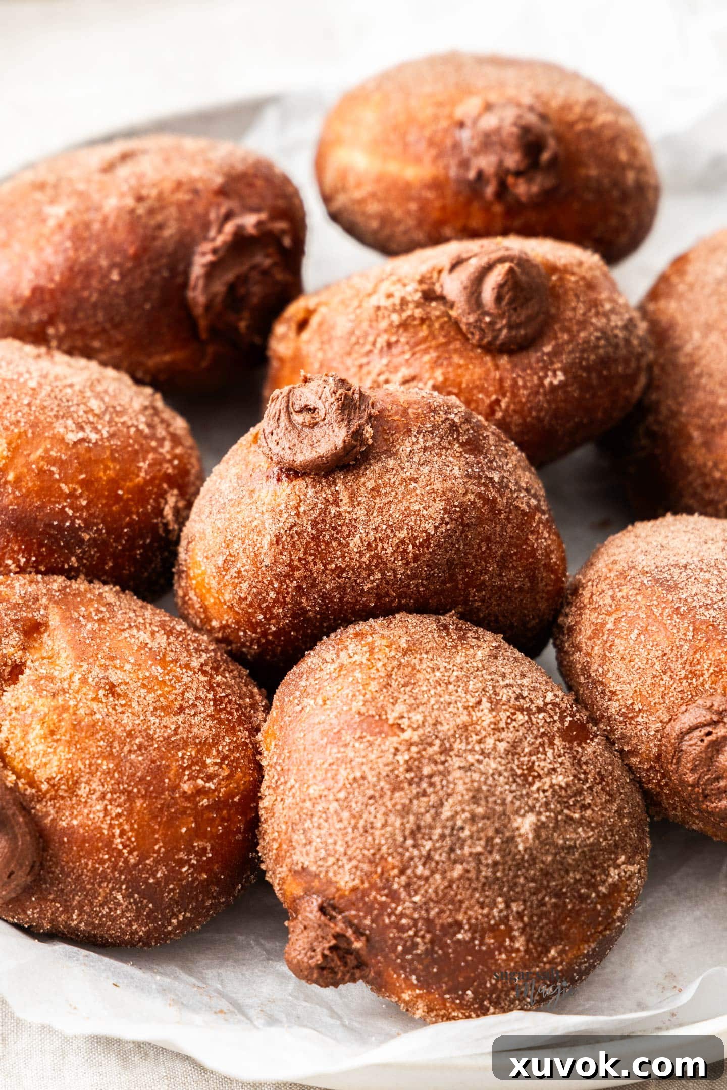 Closeup of a chocolate filled donut on a plate surrounded by more.