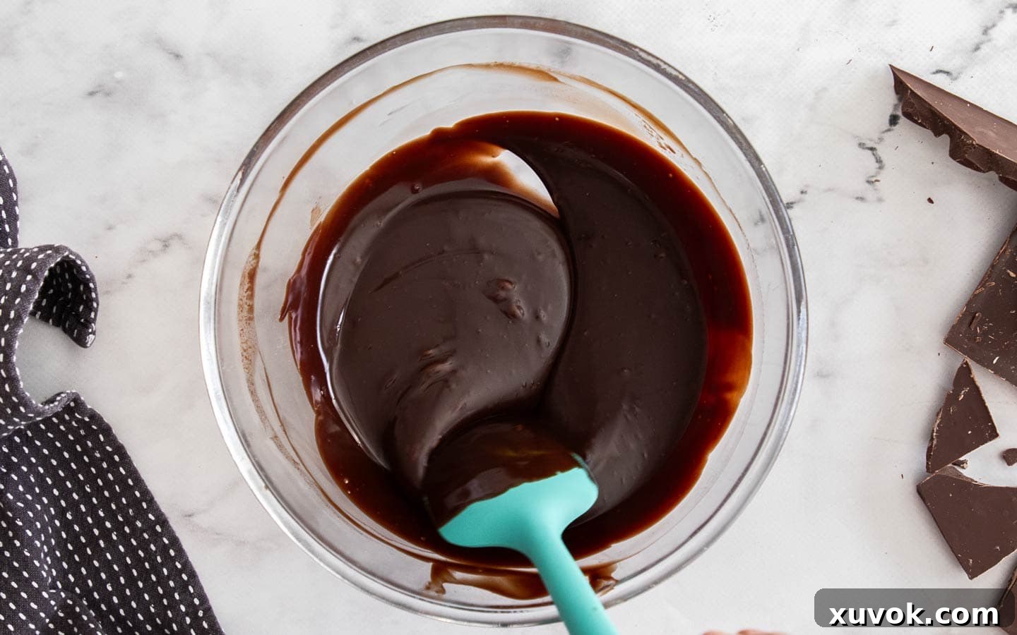 Stirring chocolate ganache in a glass bowl.