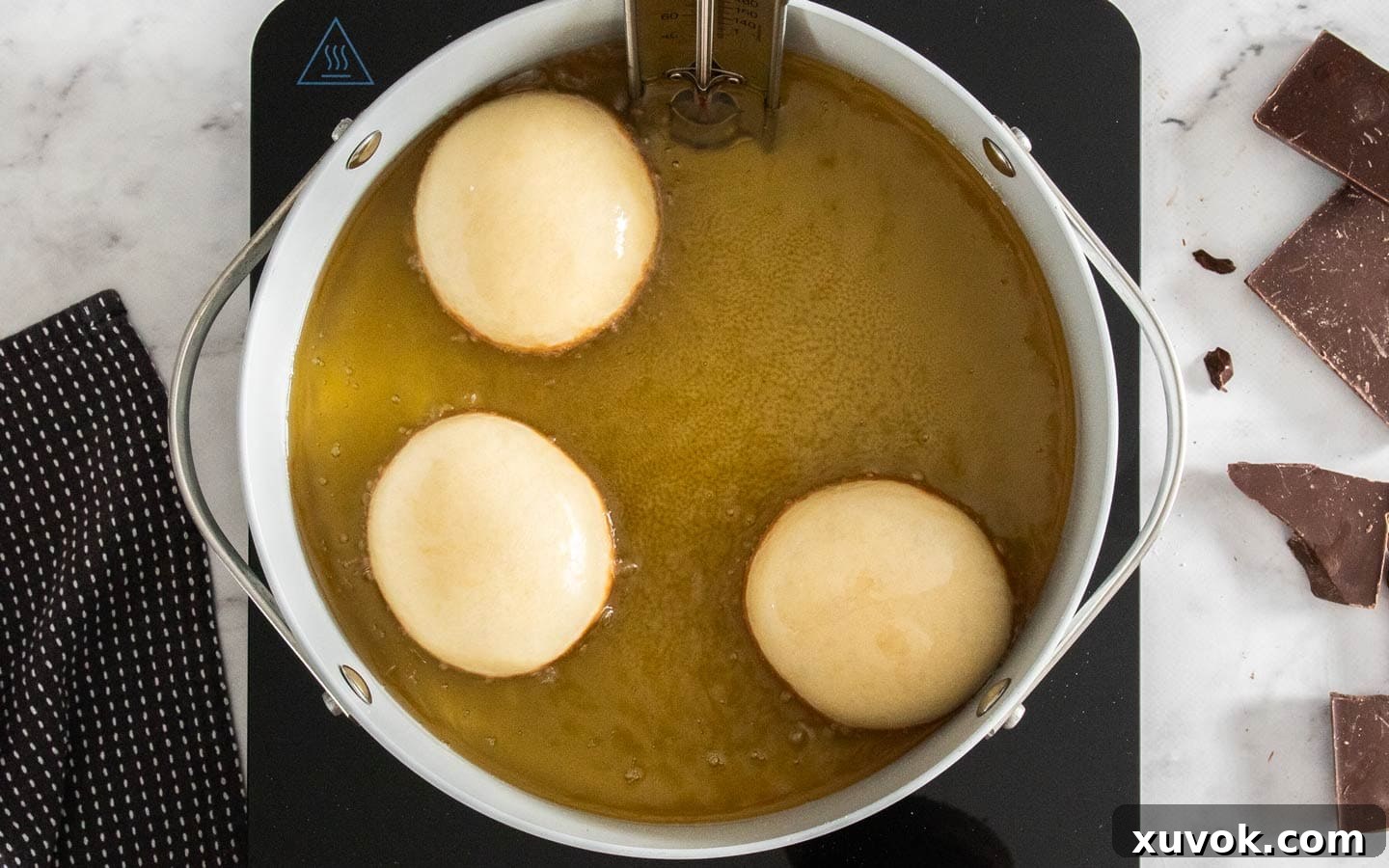 3 donuts frying in a pan of oil.