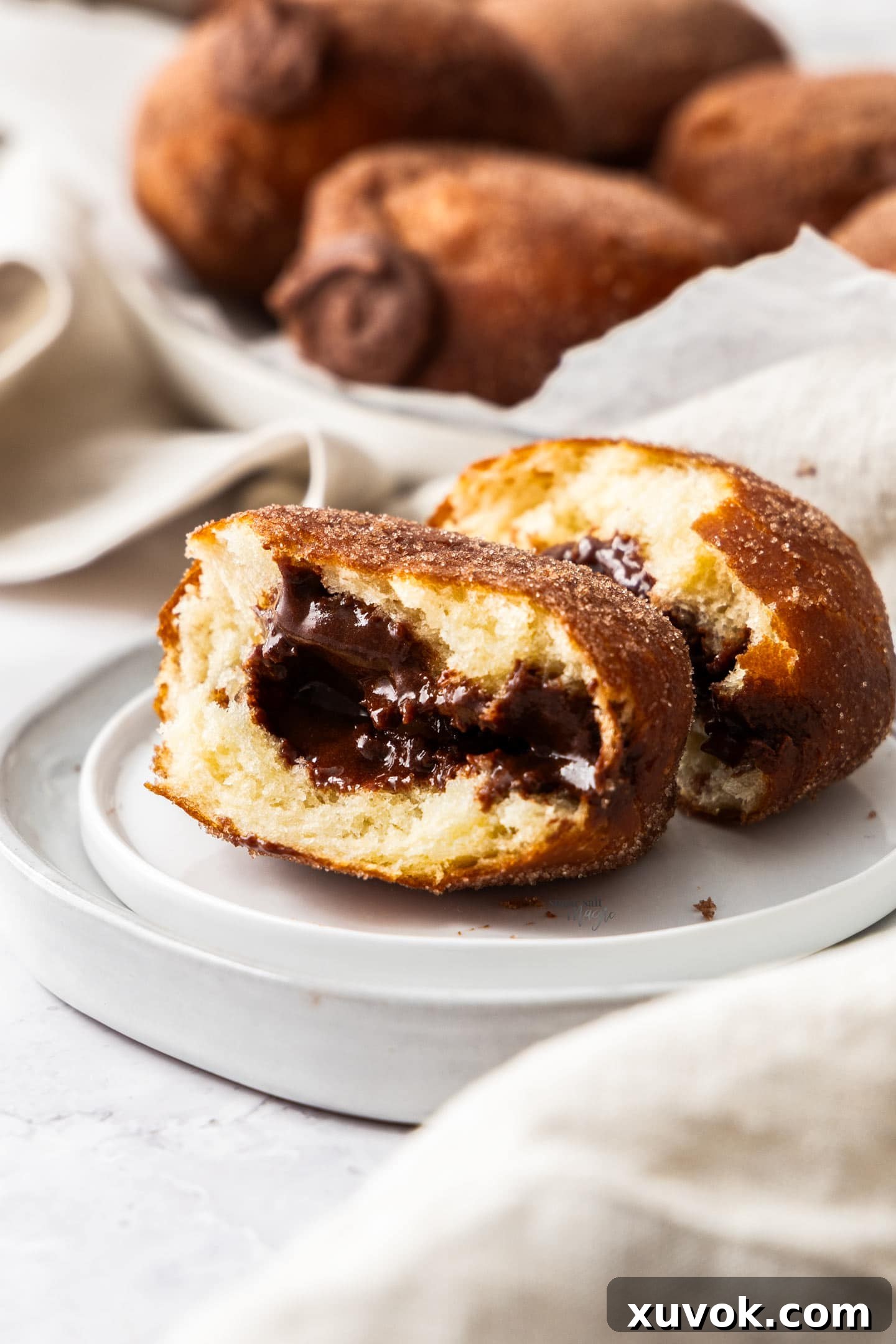 A chocolate filled donut torn in half to show the gooey ganache filling.