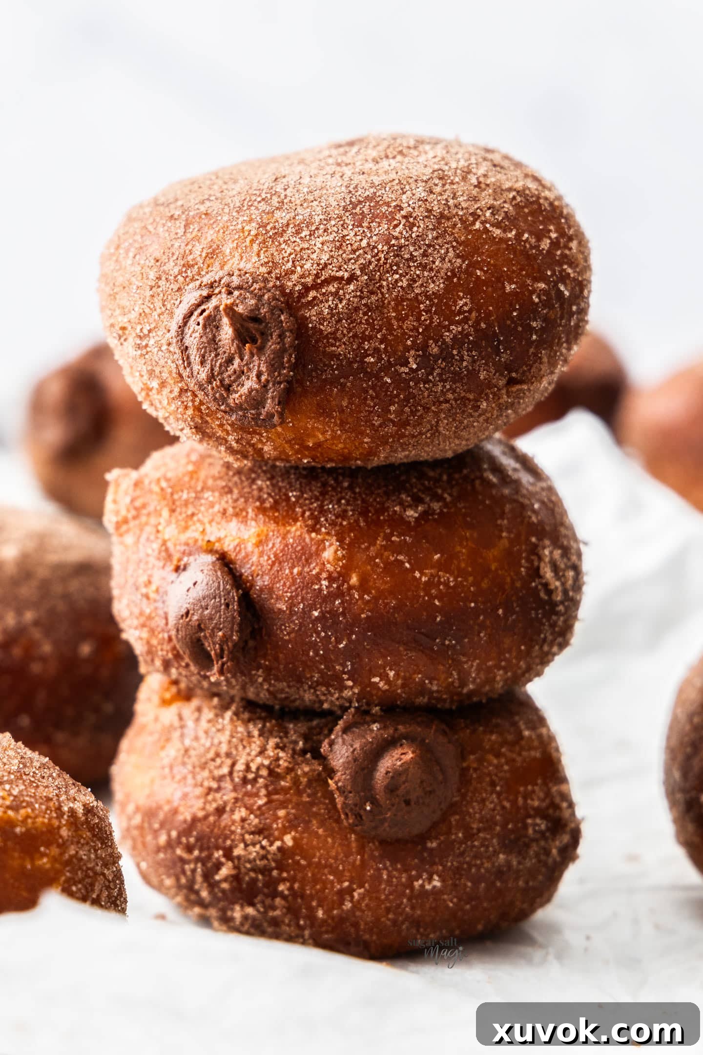 A stack of 3 chocolate filled donuts.