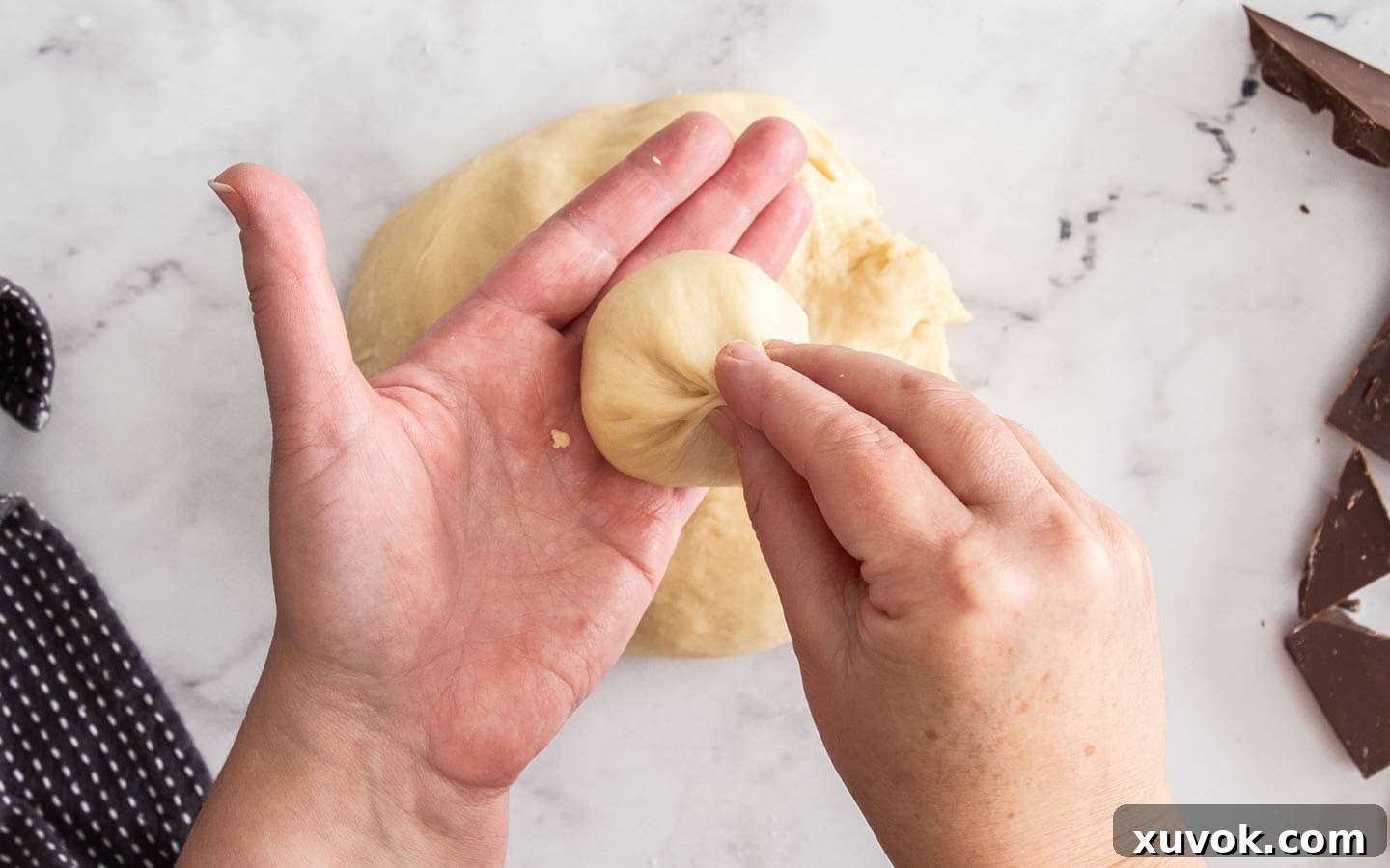 Pinching a piece of dough to form a ball.