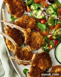 Top down view of crumbed lamb cutlets on a platter with salad.