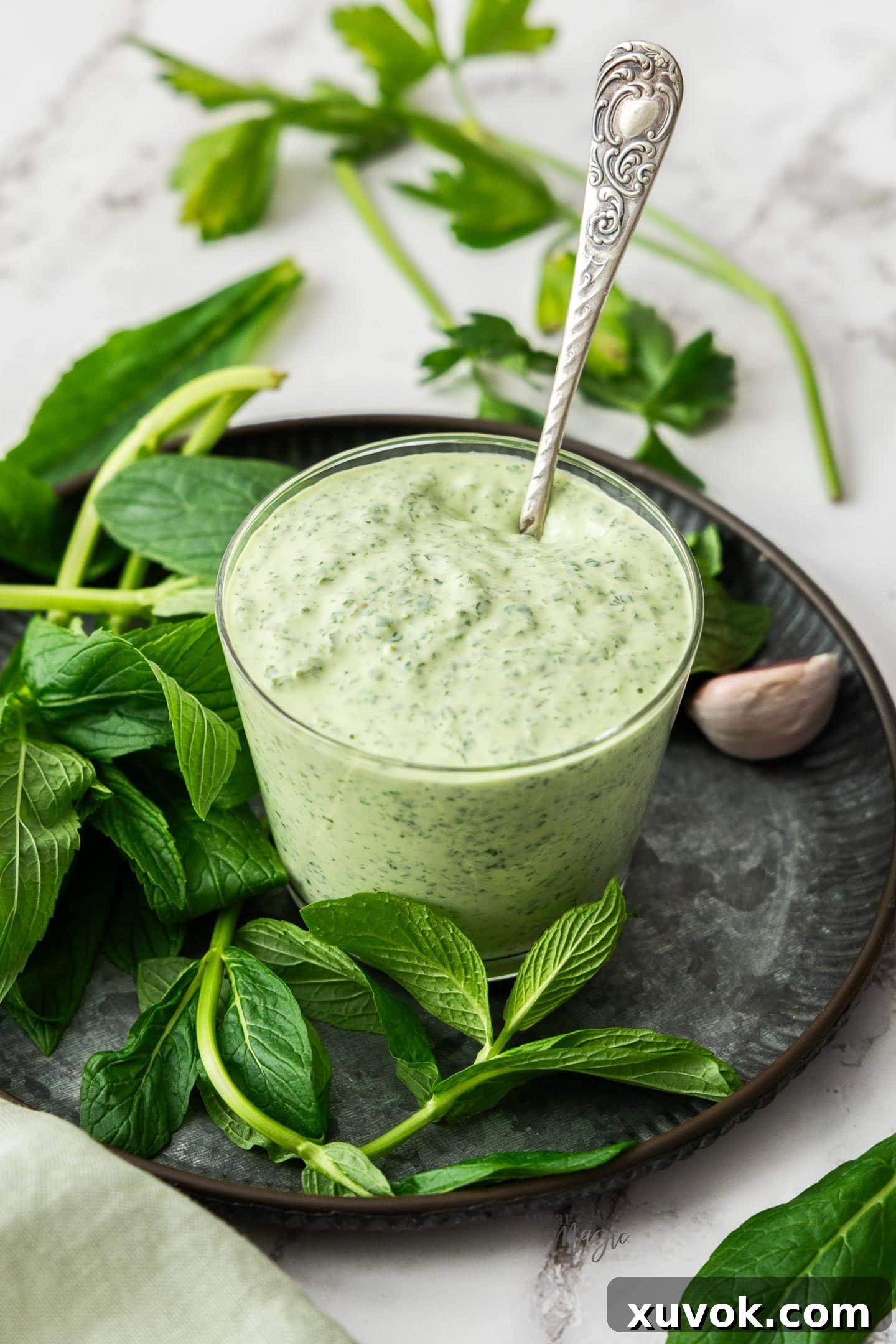 A glass of homemade minted mayo with a spoon sticking out, ready to be served.