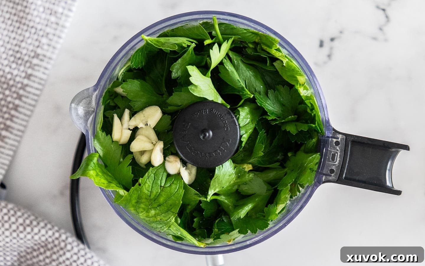 Fresh herbs, apple cider vinegar, and garlic in a mini food chopper, before processing.