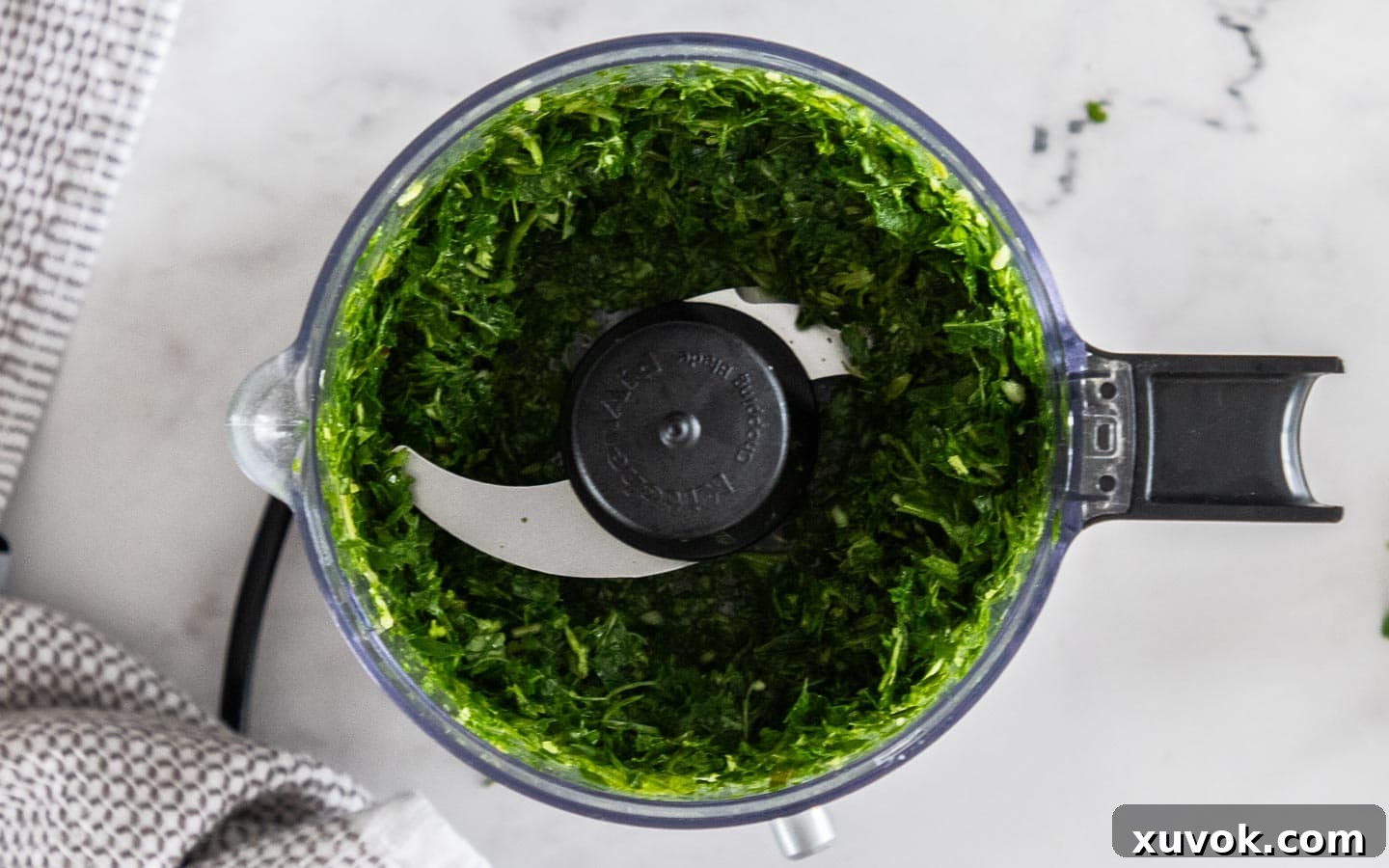 Finely chopped herbs, garlic, and apple cider vinegar, after being processed in a mini food chopper, ready for the next ingredients.