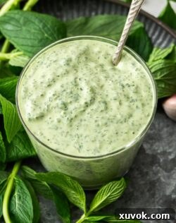 Closeup of vibrant green minted mayo in a glass, ready for serving.