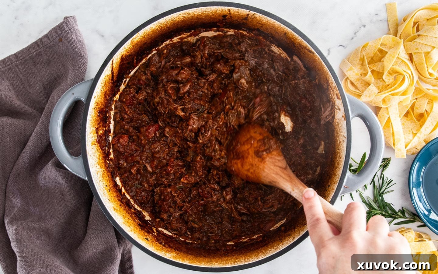 Shredding the meat with the wooden spoon in the Dutch oven.