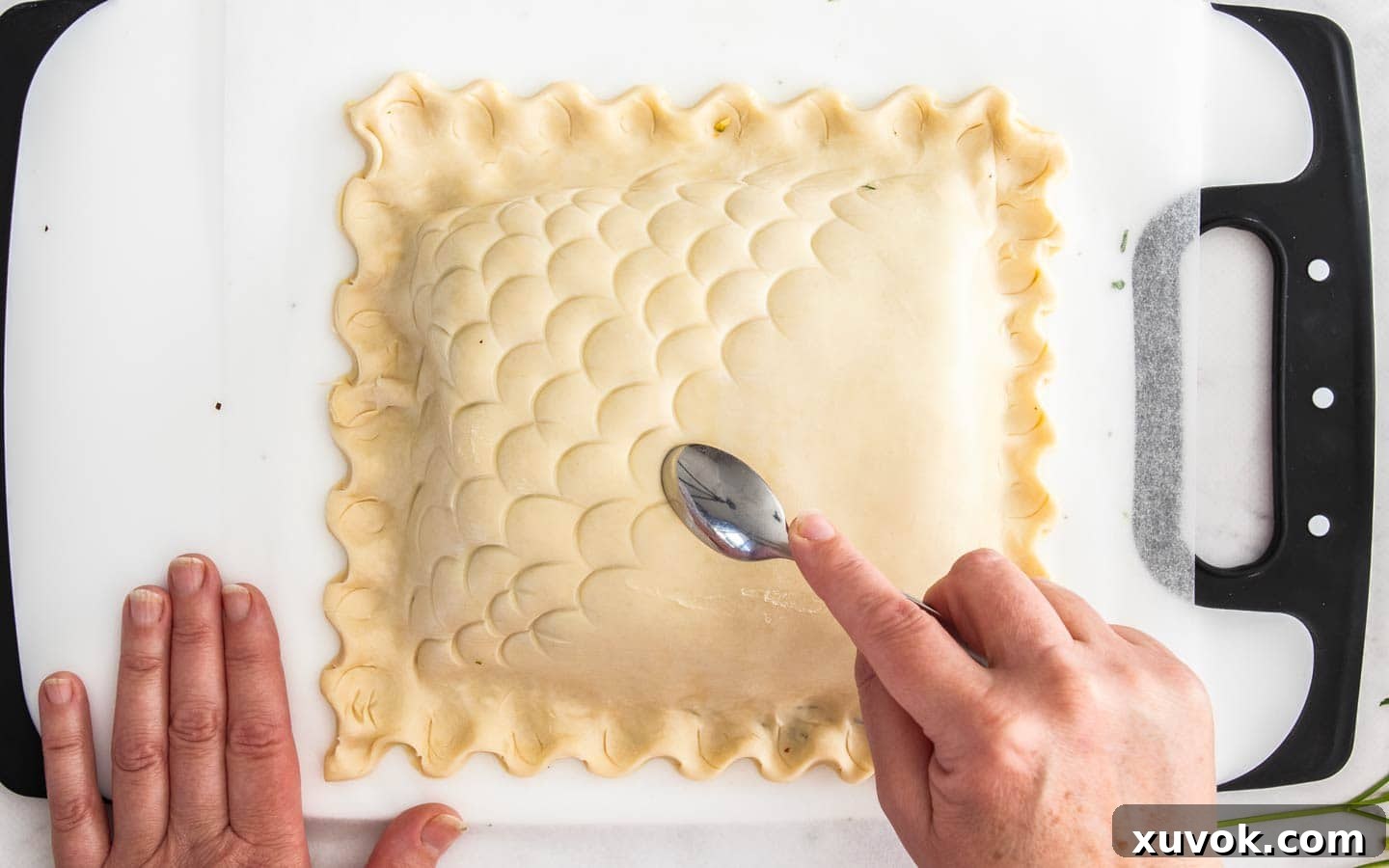 Using a spoon to create a fish scale pattern on top of the Salmon Wellington pastry.