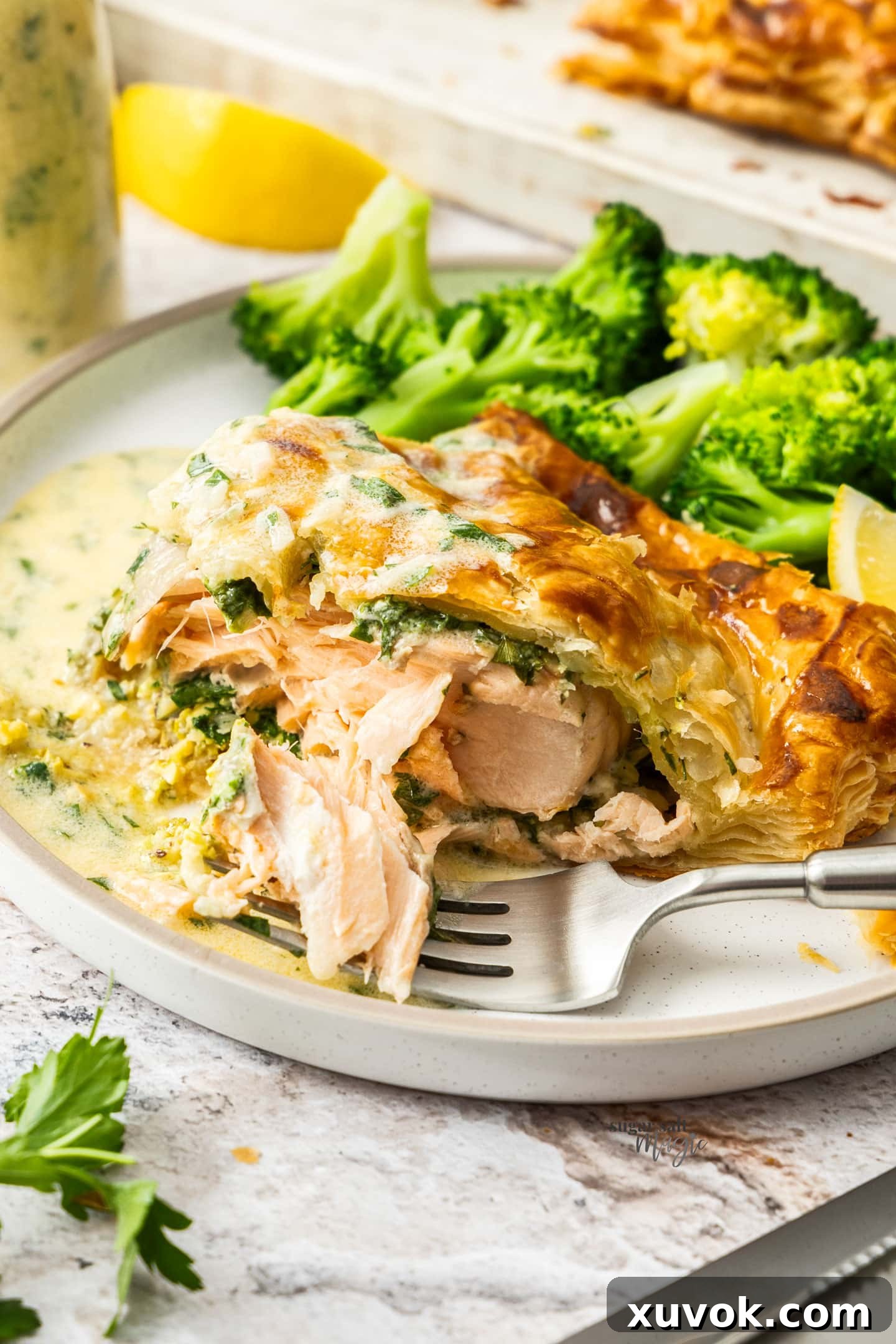 Some salmon flaked away from the salmon en croute, showing its tender texture.