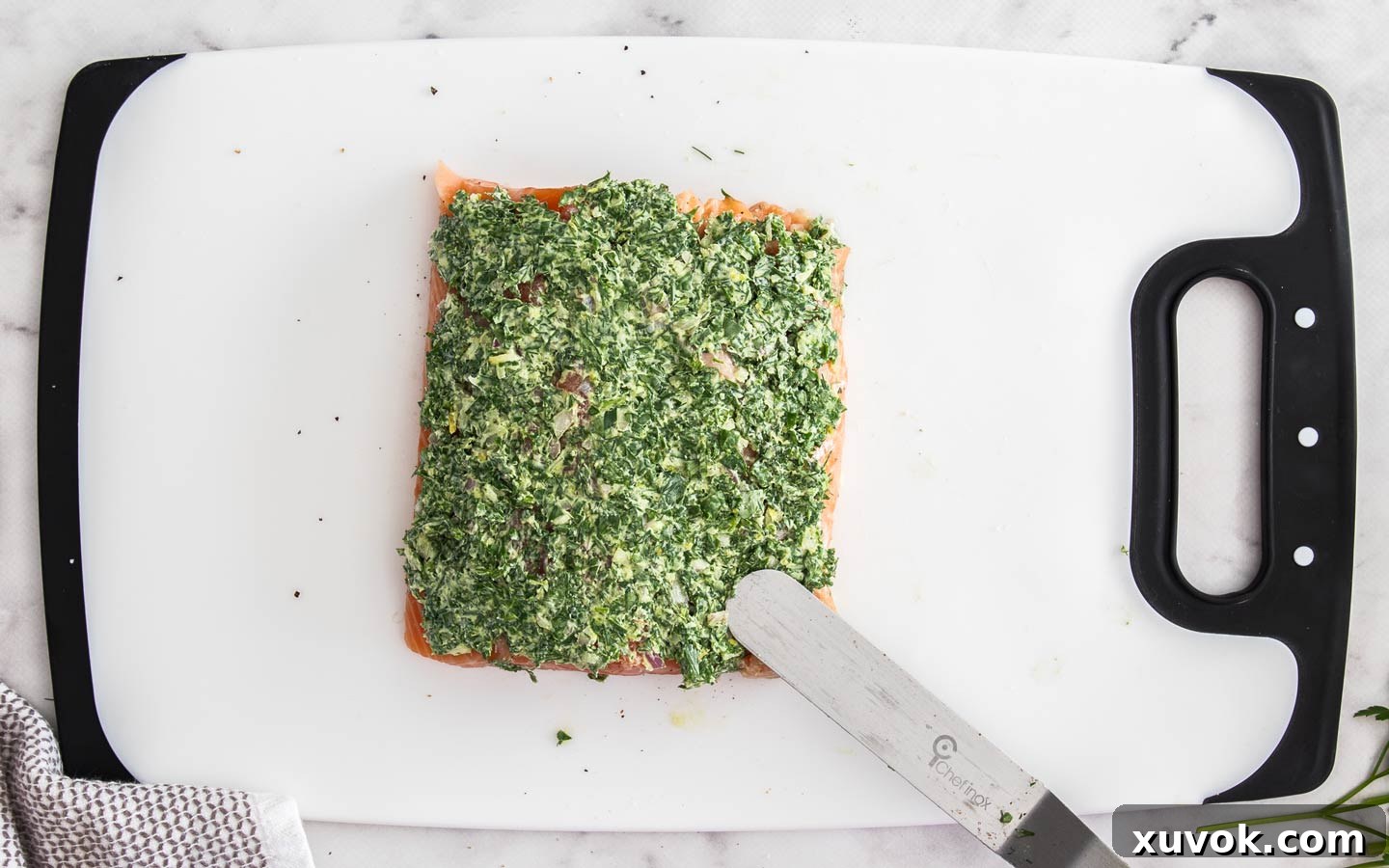 Spreading the herb mixture over the salmon fillet for the Wellington.