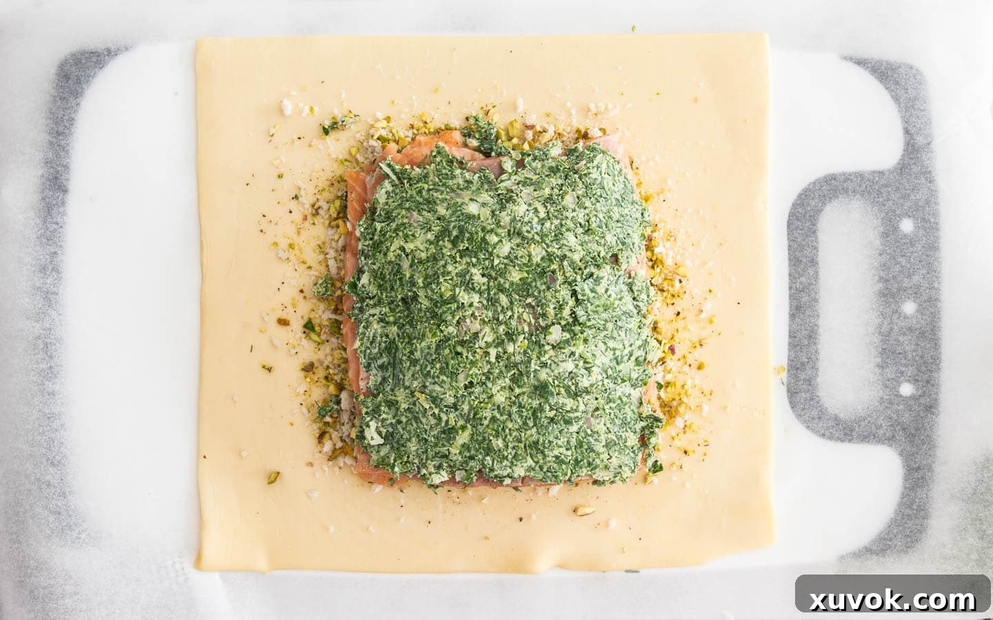 The salmon on the puff pastry, topped with the herb mixture, ready for the second pastry layer.