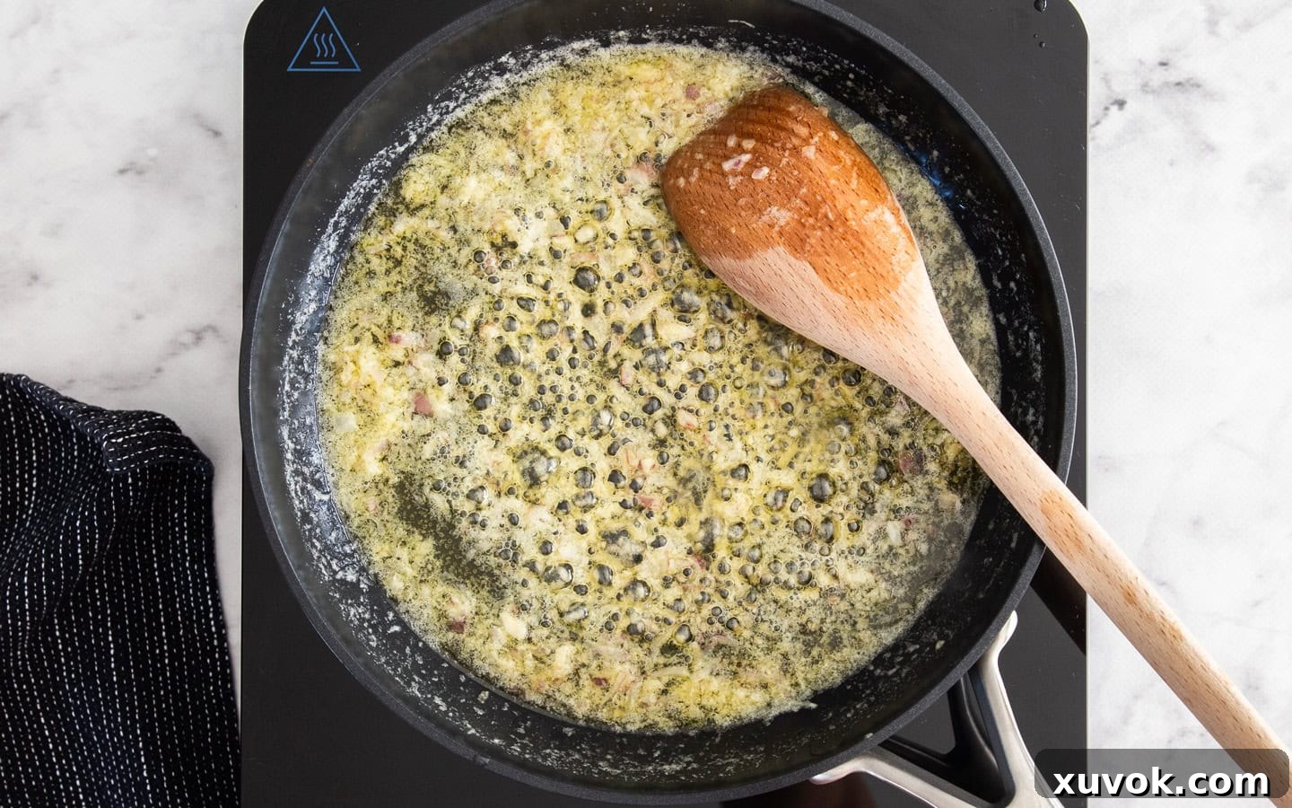 Finely chopped shallots and minced garlic sizzling gently in melted butter and oil in a pan, releasing their aromatic flavors and building a savory foundation.