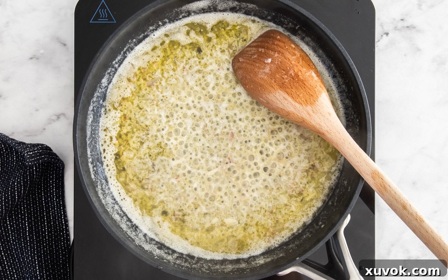 Close-up of dry white wine simmering and reducing in a pan after aromatics have been sautéed, intensifying its flavor and preparing the base for a rich sauce.