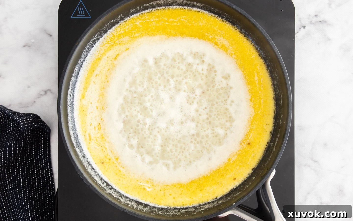 Thickened cream and vegetable stock simmering gently in a saucepan, slowly reducing and forming the rich, smooth base for the white wine sauce.