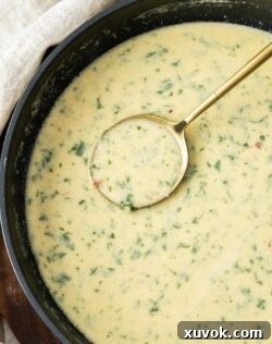 A pan of creamy white wine sauce with a spoon in it, invitingly rich and ready to be served over your favorite dish.