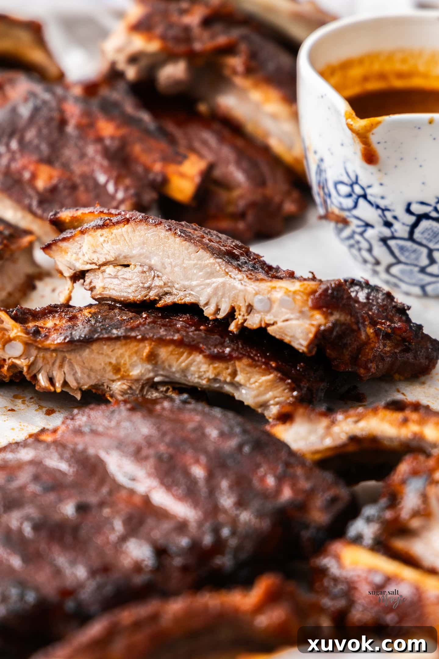 Close-up of a slow cooker BBQ pork rib, cut to reveal its tender, juicy interior and glistening sauce.