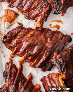 Closeup of the top of a BBQ slow cooker pork rib with a basting brush next to it.