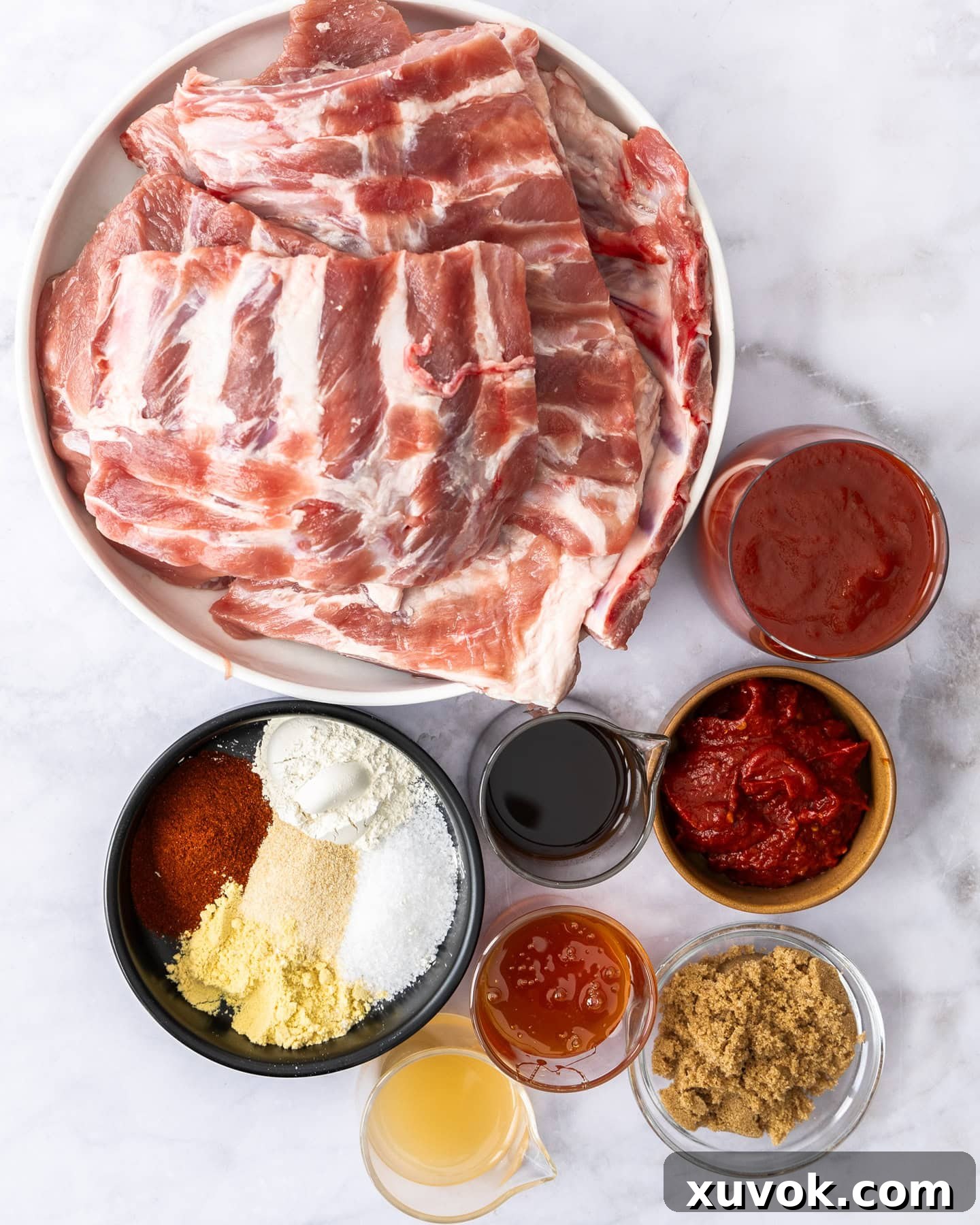 All the fresh ingredients for BBQ slow cooker pork ribs laid out on a clean marble surface.