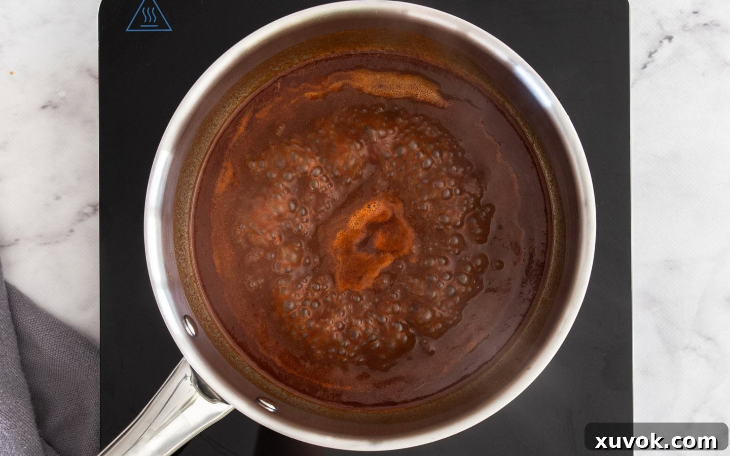 The BBQ sauce simmering in a saucepan over medium-high heat, reducing to a thicker consistency.