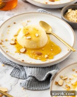 Honey panna cotta on a plate with honey and nuts.