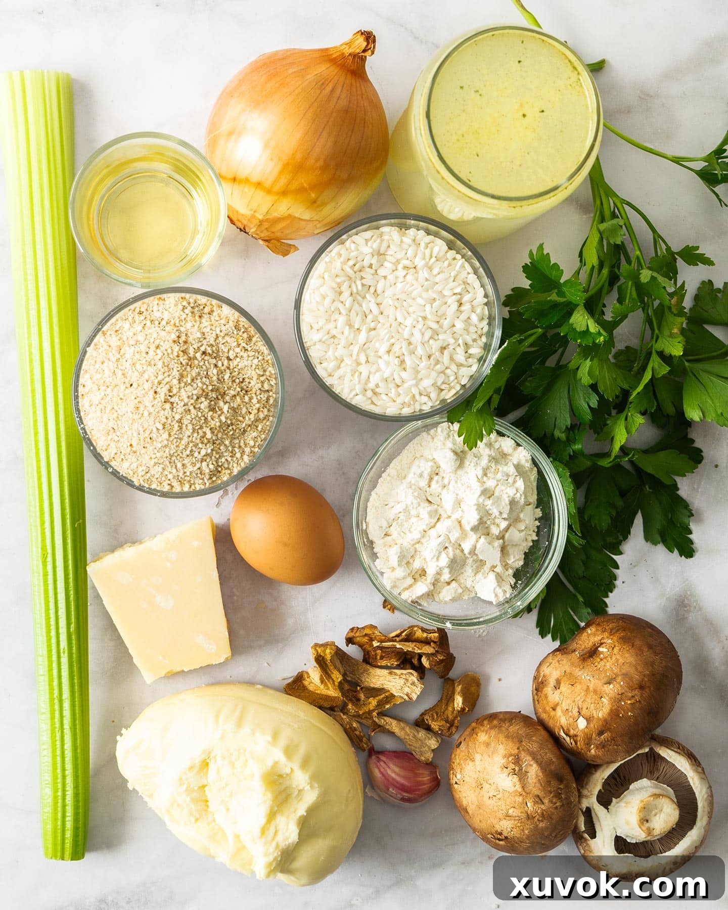 A collection of fresh ingredients laid out on a wooden surface, including Swiss brown mushrooms, dried porcini, Arborio rice, Parmesan, and mozzarella, ready for making mushroom arancini.