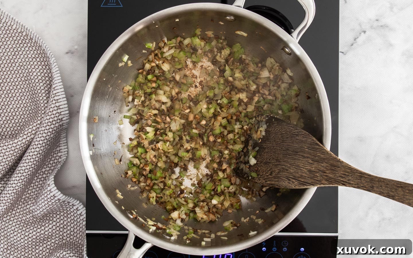 A mix of finely chopped onions, celery, and garlic cooking alongside the browned mushrooms in a pan, softening and releasing their aromatic scents.