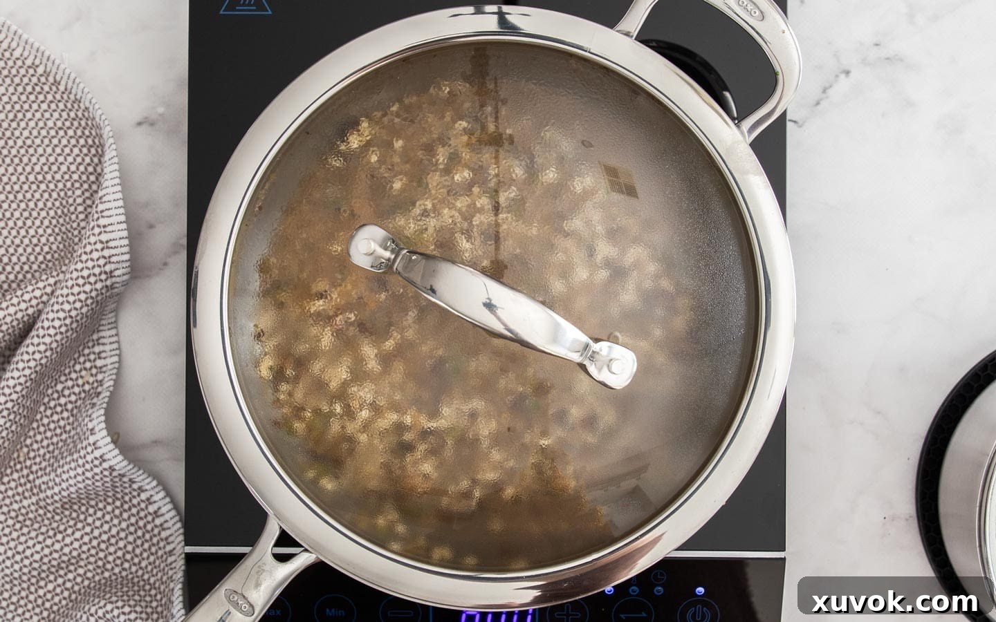 A lidded pan of mushroom risotto gently simmering on the stovetop, allowing the rice to slowly absorb the stock.