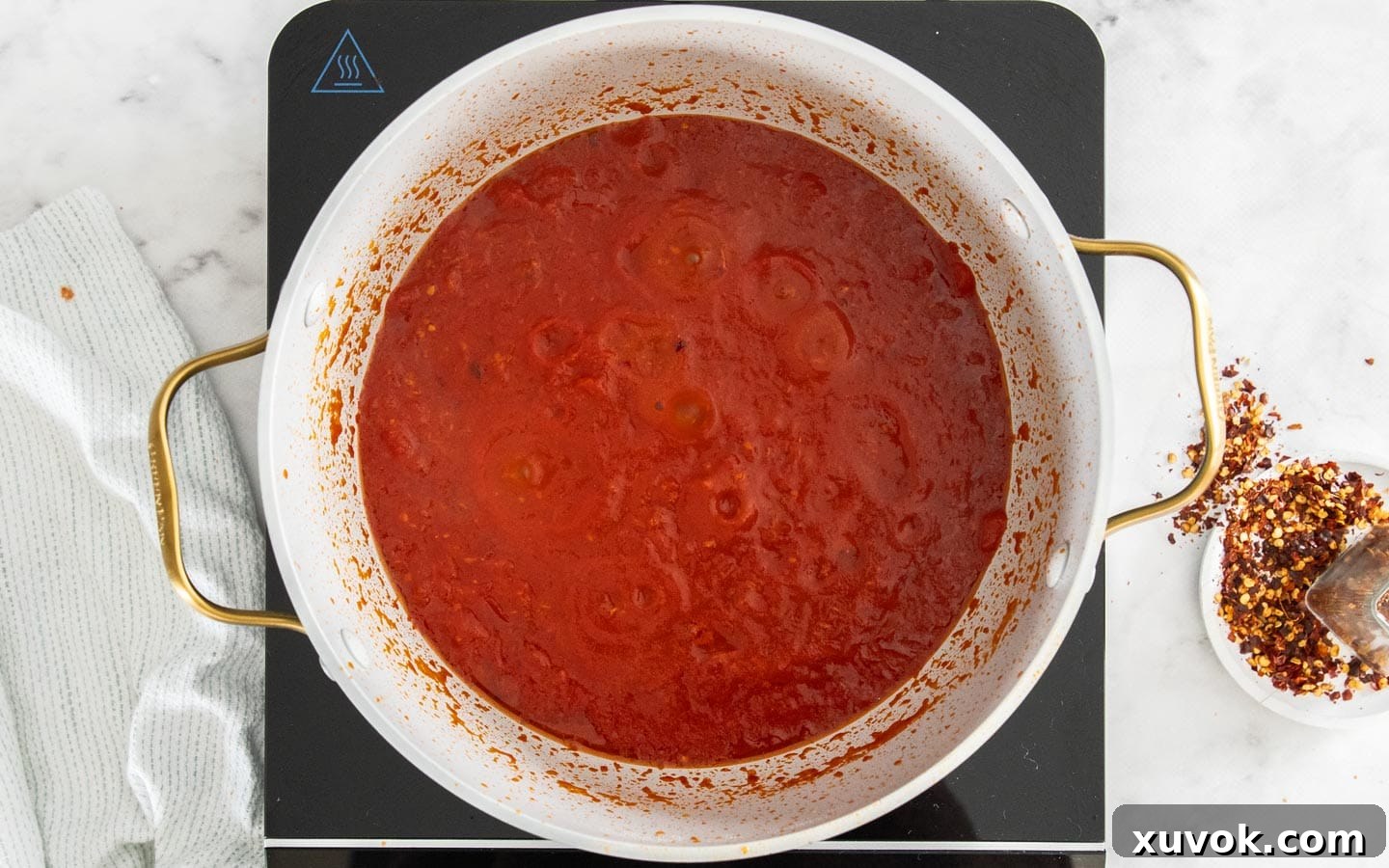 The arrabbiata sauce gently simmering in the pan, reducing and thickening.