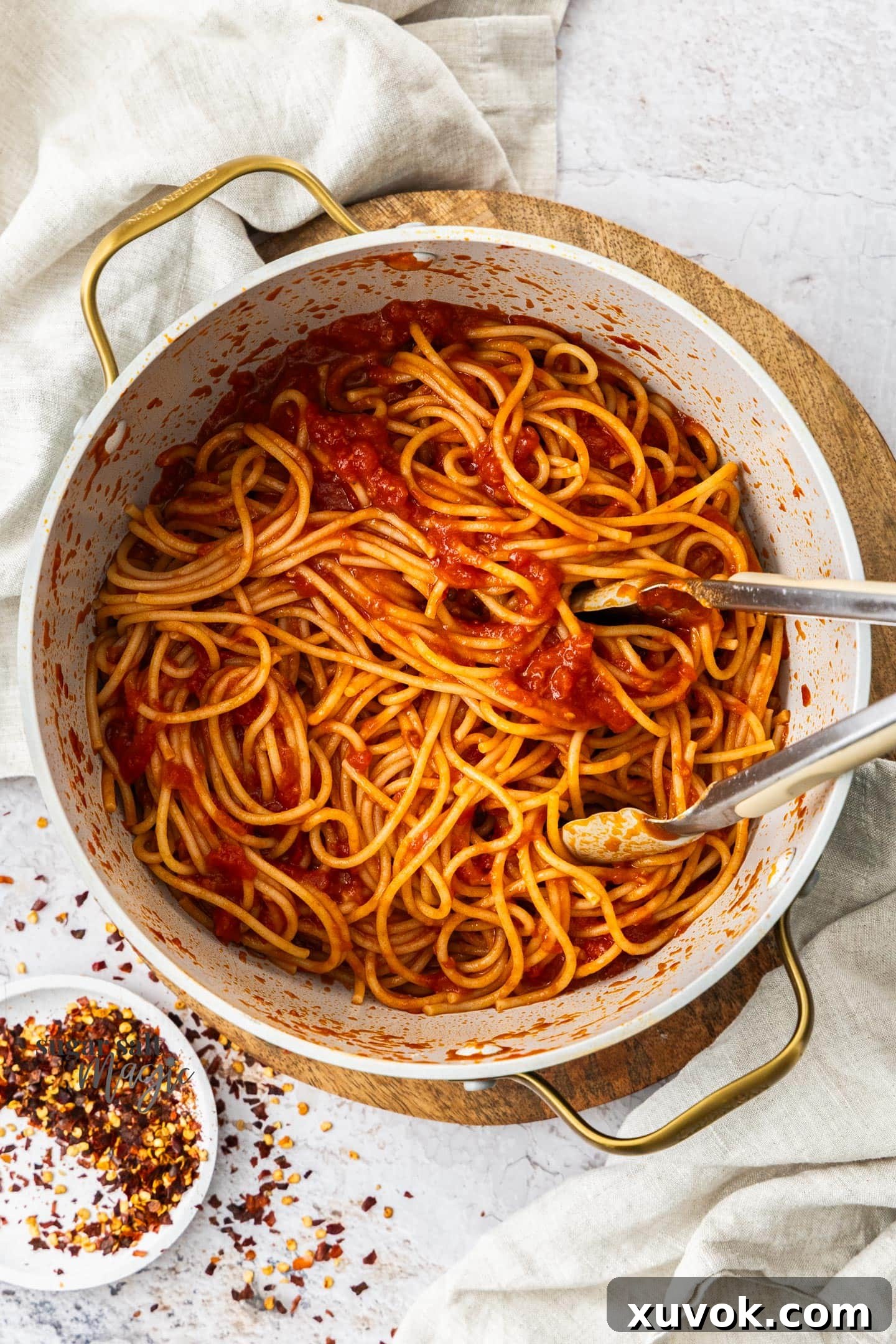 Top down view of spaghetti arrabbiata in a pan, garnished with fresh basil.