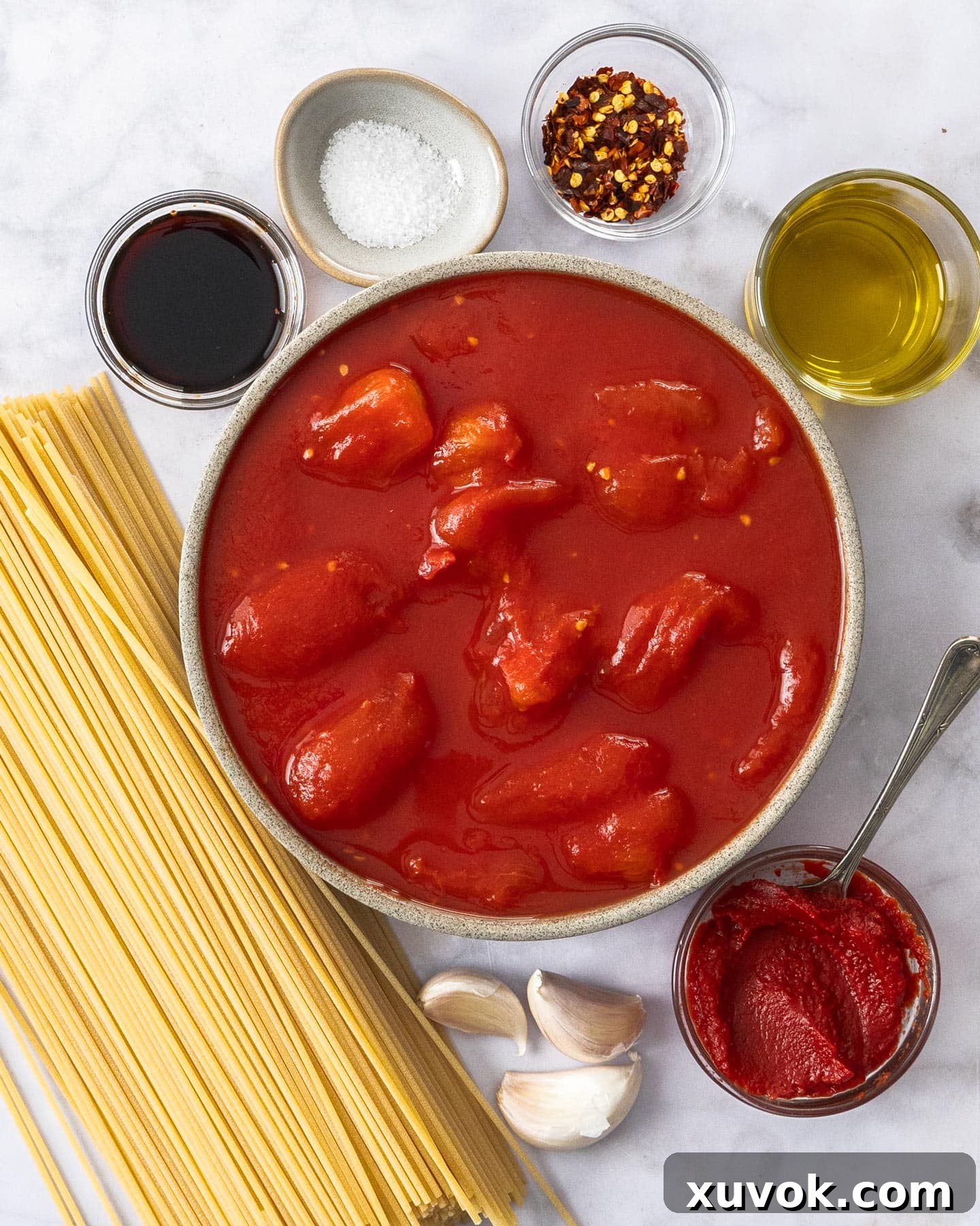 Fresh ingredients laid out for making spaghetti arrabbiata, including tomatoes, garlic, chili, and olive oil.